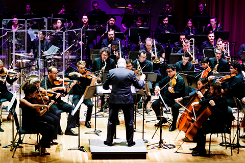 A conductor guiding an orchestra during a performance at the Frost School of Music